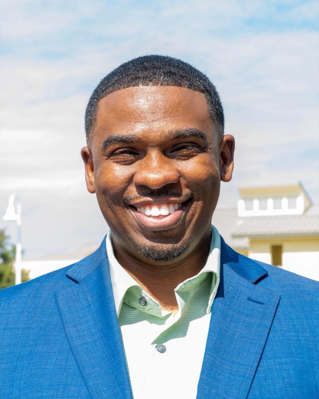Milan Balinton smiling outdoors in San José, wearing a blue suit